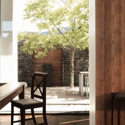 Sala de jantar com mesa, cadeira e porta aberta para jardim com árvore