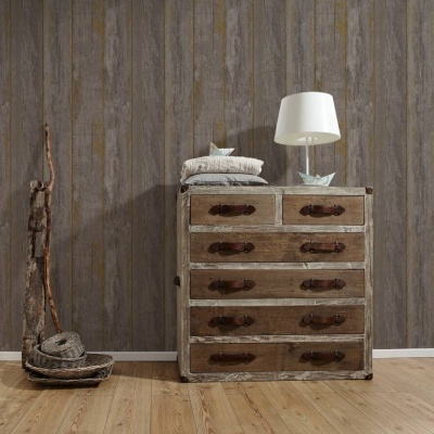 Cómoda rústica em madeira com cinco gavetas e decoração com corda em ambiente com parede e chão de madeira.