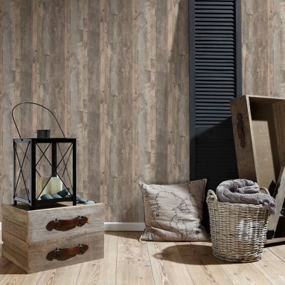 Decoração com candeeiro, caixas de madeira, almofada, cesta de vime e manta contra parede de madeira clara