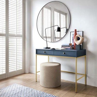 Mesa de escritório azul com gavetas, banco begue, espelho redondo e decoração em ambiente claro