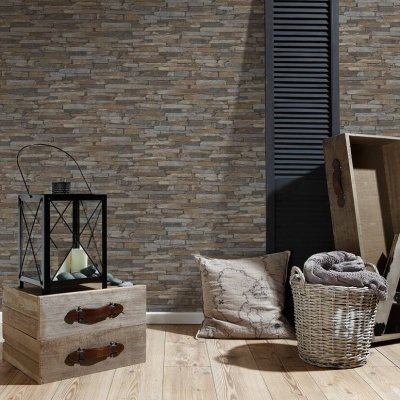 Decoração interior com caixa de madeira, candeeiro, almofada, cesta de vime e escada pequena em frente a parede de tijolos.