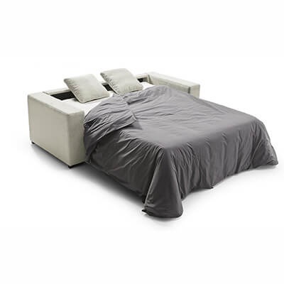 Sofá-cama cinzento claro transformado em cama com cobertor cinzento escuro num fundo branco