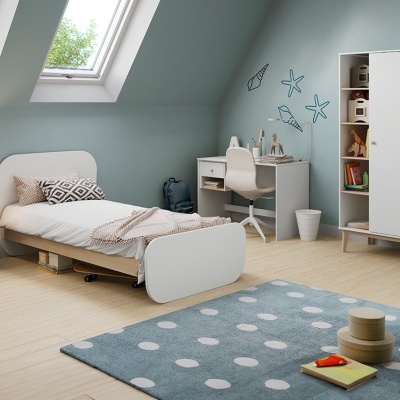 Quarto infantil com móveis claros, tapete azul com bolinhas e decoração marinha