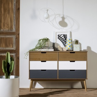 Cómoda de madeira com quatro gavetas coloridas, planta suculenta em vaso branco, lâmpada pendente minimalista