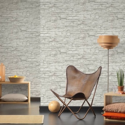 Cadeira de couro castanho com estantes de madeira, candeeiro de pé e planta junto a parede de padrão pedra cinza.