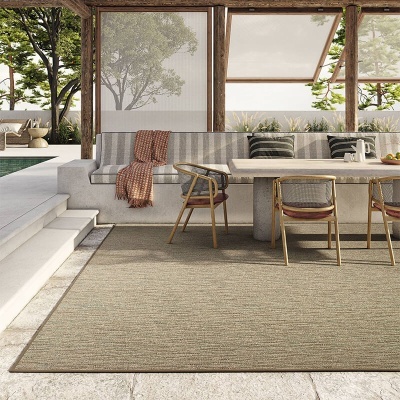 Área de estar exterior com sofá, mesa, cadeiras e tapete bege