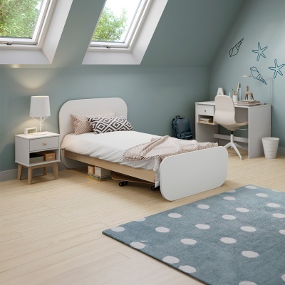 Quarto com cama individual branca, mesa de cabeceira, secretária, cadeira e tapete azul com pontos brancos.