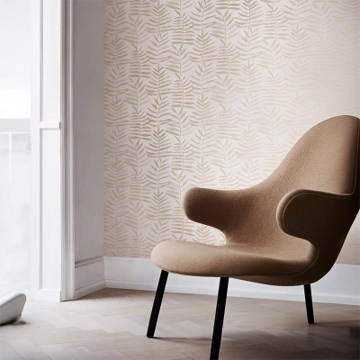 Cadeira castanha clara com pernas pretas numa sala com papel de parede bege com padrão de folhas