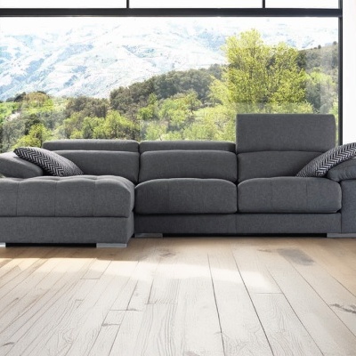 Sofá modular cinza escuro com chaise longue, almofadas decorativas, piso de madeira e vista para montanhas