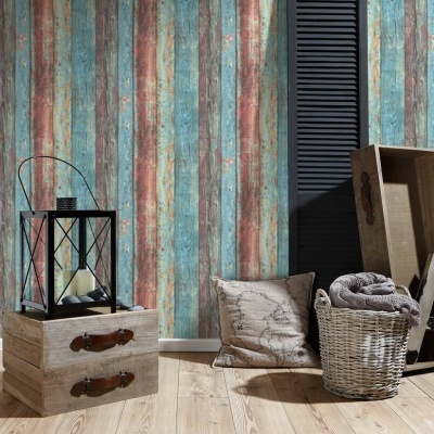 Sala com parede listrada, candeeiro preto, caixas de madeira, almofadas, cesto com cobertor e escada de madeira