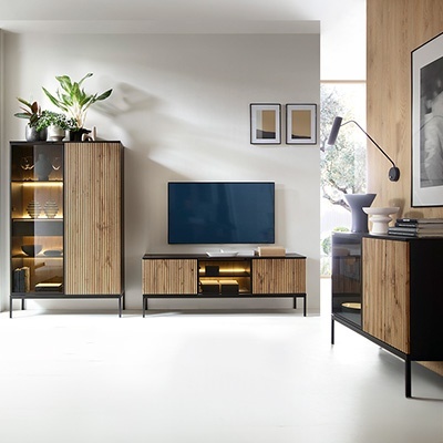 Conjunto de móveis de sala de estar em madeira clara com estrutura preta, televisão e decoração