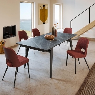 Mesa de jantar com tampo de pedra e cadeiras vermelhas num ambiente interior moderno