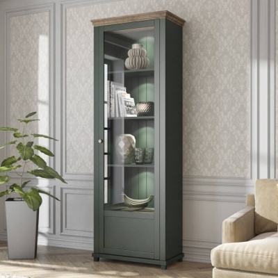 Vitrine verde escuro com vidro, objetos decorativos nas prateleiras, sala clássica com planta e sofá bege