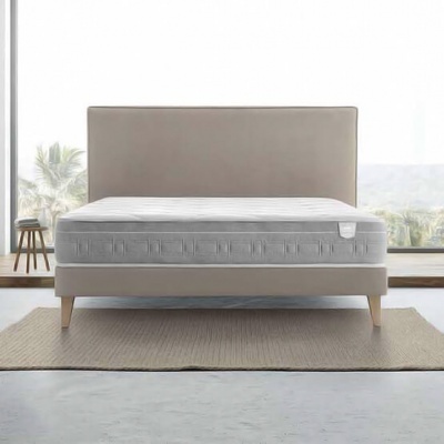 Cama de casal com colchão cinzento sobre tapete bege