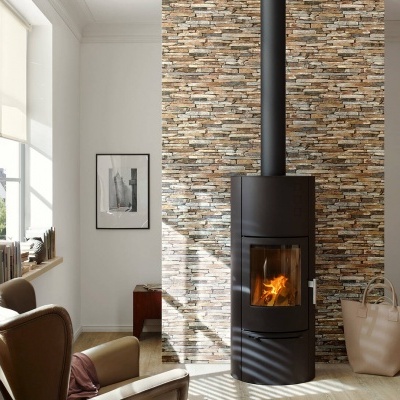 Lareira moderna cilíndrica preta com vidro em parede de pedras decorativas e poltronas de couro