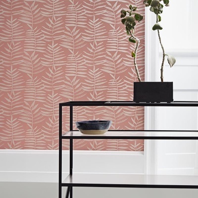 Papel de parede rosa com padrão de folhas brancas, estante preta com vaso e recipiente