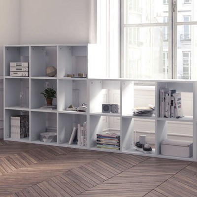 Estante modular branca com diversos objetos, livros e plantas, numa sala com chão de madeira clara.