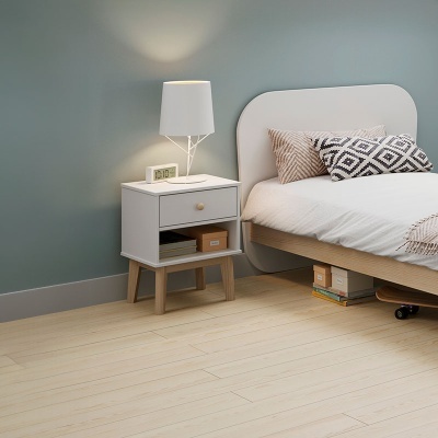 Mesa de cabeceira branca com candeeiro ao lado de cama com almofadas geométricas