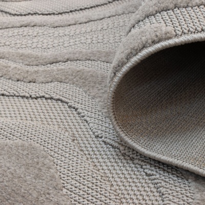 Tapete cinzento com padrões ondulados em relevo e texturas variadas enrolado