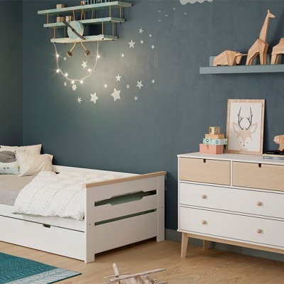 Quarto infantil com cama branca, cómoda branca e decoração temática de estrelas