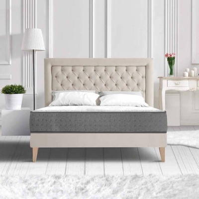 Cama estofada bege com colchão cinzento e decoração de quarto clara