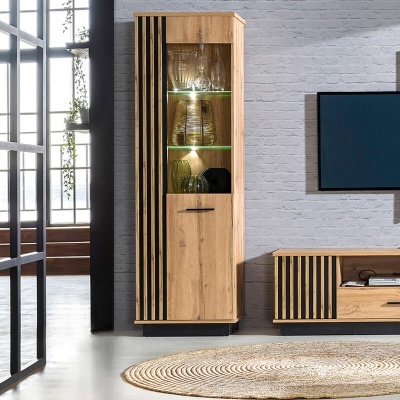 Móvel alto em madeira clara com ripados pretos e porta de vidro iluminada num ambiente interior