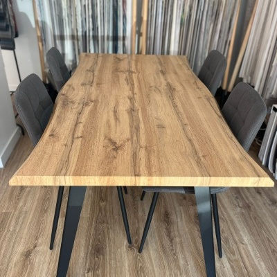 Mesa de madeira clara com pernas metálicas pretas e cadeiras cinzentas em ambiente de loja