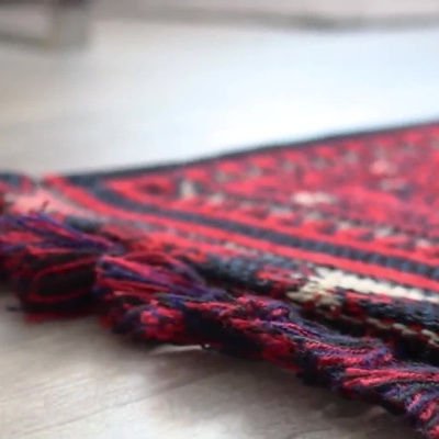 Mesa de jantar com cadeiras azuis sobre tapete vermelho com padrão tradicional