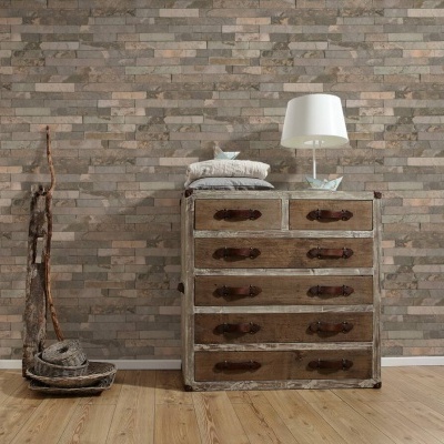 Móvel de madeira envelhecida com seis gavetas contra parede de tijolos cinzentos e marrons e chão de madeira clara