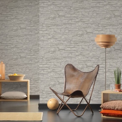 Sala com cadeira castanha de metal, candeeiro de madeira e papel de parede cinzento com padrão de pedra