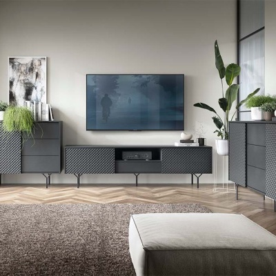 Sala de estar com móveis pretos texturizados, tapete castanho, televisão na parede e plantas