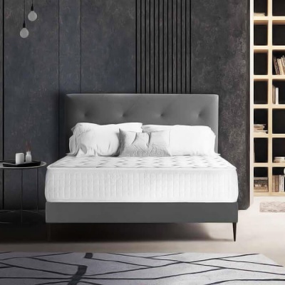 Cama com colchão branco, cabeceira cinza e almofadas brancas em ambiente moderno