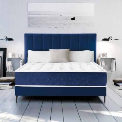 Cama de casal azul com colchão branco e cabeceira acolchoada sob quadro preto e branco