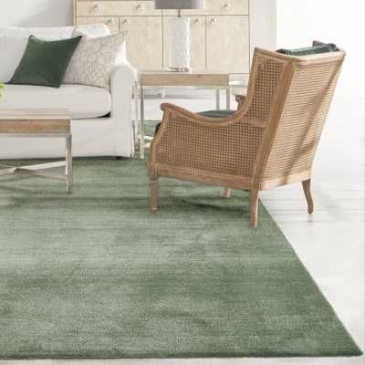 Tapete verde claro macio em sala com cadeira de madeira e palhinha, sofá branco e mesas de madeira e metal.