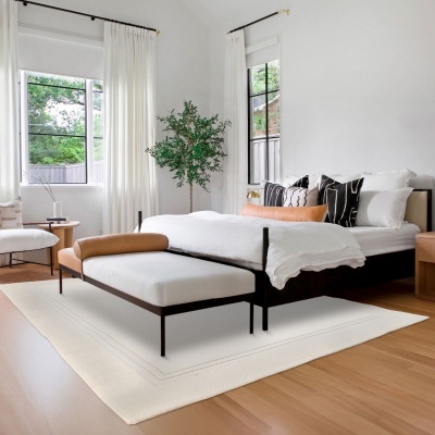 Quarto moderno com cama preta, roupa de cama branca e almofadas coloridas