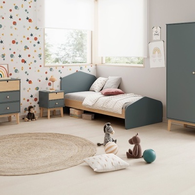 Quarto infantil com móveis azuis e madeira clara, papel de parede às estrelas e tapete redondo de fibras naturais