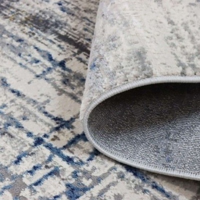 Tapete abstrato azul, cinzento e branco com textura felpuda e bordas costuradas