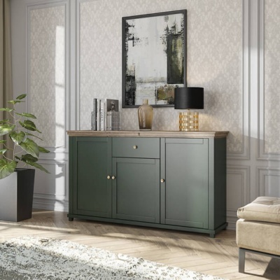 Móvel verde escuro com tampo de madeira, abajur preto dourado, planta em vaso e cadeira bege