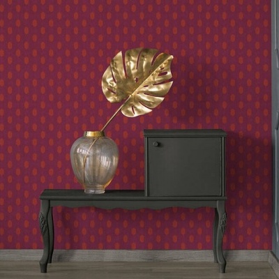 Mesa preta com vaso de vidro e folha dourada decorativa em parede vermelha com padrão