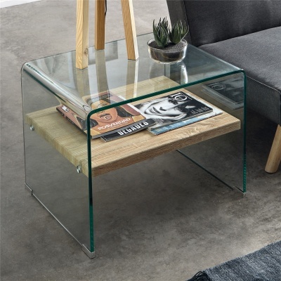 Mesa de apoio de vidro com prateleira em madeira, revistas e vaso de plantas