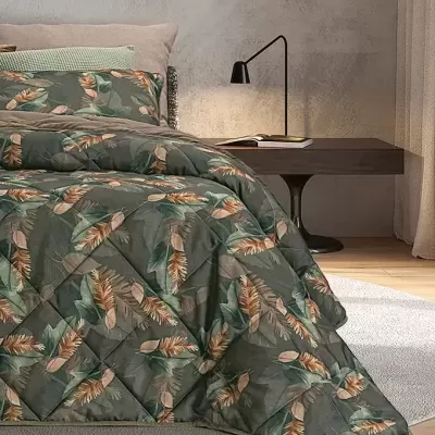 Cama com edredão estampado de folhas verdes e castanhas e almofada verde