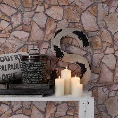 Bancada branca com almofada, vaso e velas em fundo de parede de pedra