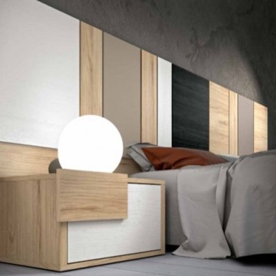 Cama com cabeceira de madeira, criado-mudo com candeeiro esférico, lençóis cinzentos e almofada castanha