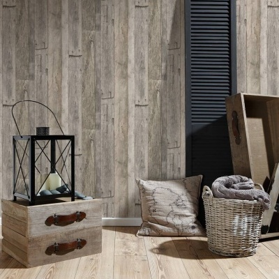 Lanterna preta, caixas de madeira, almofada, cesta com manta e parede de madeira clara.