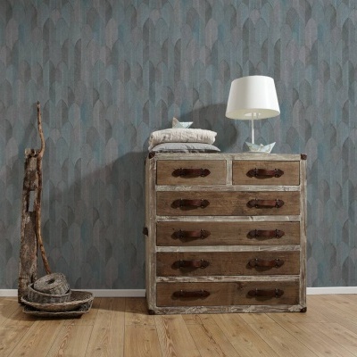 Cómoda vintage de madeira com seis gavetas e puxadores escuros, ao lado de objectos rústicos em chão de madeira e parede azul com padrão geométrico