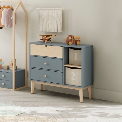 Cômoda azul com gavetas e caixas numeradas, brinquedos de madeira em cima, em ambiente claro