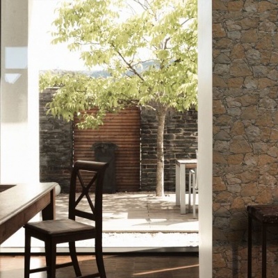 Sala de jantar com mesa e cadeira de madeira perto de parede de pedra e janela aberta para pátio