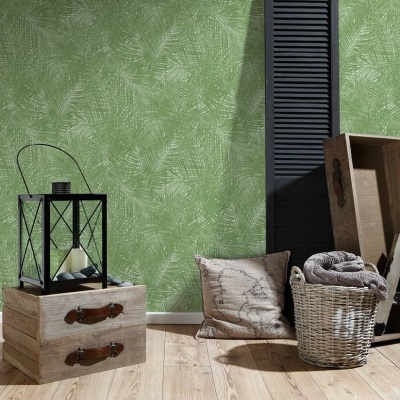 Conjunto decorativo com cômoda de madeira, lanterna preta, almofada, cesta com manta e caixa de madeira, parede verde com padrão de folhas.