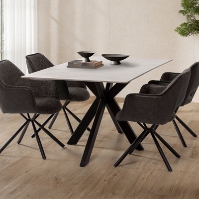 Mesa de jantar branca com pernas pretas e seis cadeiras cinza escuras num espaço interior com chão em madeira e planta ao fundo