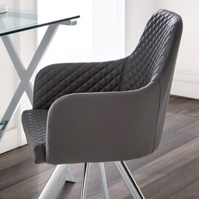 Cadeira de escritório cinzenta com padrão matelassê ao lado de mesa de vidro